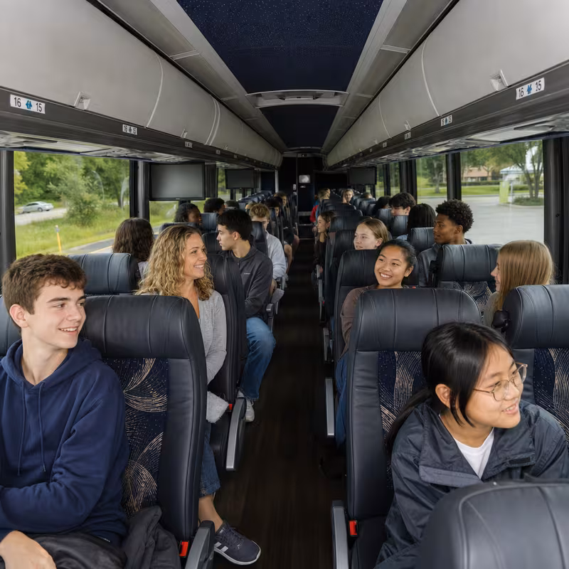 Group boarding a white charter bus for School Transportation transportation in Minneapolis